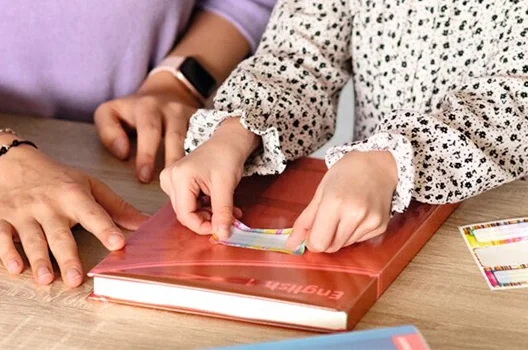 Schreibtisch mit Buch das in Buchschutzfolie eingebunden ist und Beschriftungsetikett klebend auf der Buchschutzfolie