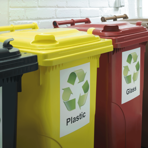 Drei Abfallbehälter für Recycling: gelb für Plastik, rot für Glas und schwarz für Restmüll, mit entsprechenden Symbolen.