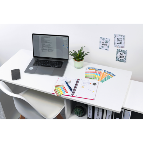 Schreibtisch mit Laptop, Notizbuch, bunten Notizen und einer Pflanze. An der Wand hängen inspirierende Zitate.