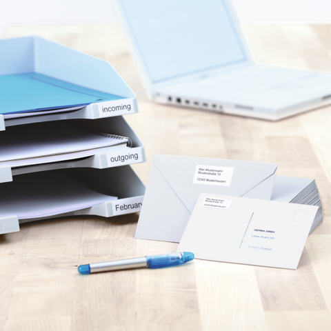 Blaue Kunststoffbox mit einer Etikette, die die Nummer 0134 zeigt, steht auf einem Tisch neben einem Notizblock und einem Stift.