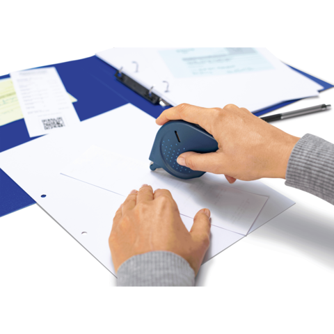 Eine Hand hält einen blauen Stempel, der auf ein Blatt Papier gedrückt wird. Im Hintergrund sind ein Ordner und einige Dokumente sichtbar.