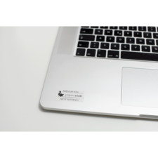 Ein Laptop mit einer Tastatur und einem Aufkleber, der "EIGENTUM VON paperswan" und "NICHT ENTFERNEN" zeigt.