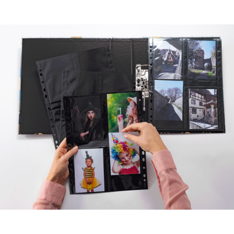 Eine Person blättert durch ein Fotoalbum mit mehreren Bildern, darunter Porträts von Kindern und Erwachsenen in verschiedenen Kostümen.