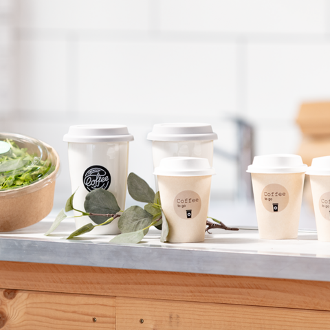 Eine Person hält ein beschriftetes Kuvert mit dem Namen "Michael Gerd" und weiteren Kuverts sowie Adressetiketten im Hintergrund.