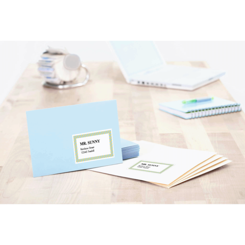 Blaue Karte mit dem Namen "MR. SUNNY" und der Aufschrift "Tischkarte" auf einem Holztisch, umgeben von weiteren Briefen und Büromaterial.
