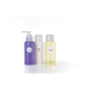 Drei Flaschen mit Pflegeprodukten: eine lila Flasche mit Spülung, eine weiße Flasche mit Creme und eine gelbe Flasche mit Shampoo.