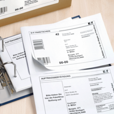 Paketscheine und Auftragsbestätigungen in einem Ordner, mit Adressdaten und Barcode für den Versand in Deutschland.