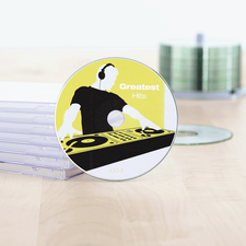 CD intitolata 'Greatest Hits' con un design da DJ, circondata da custodie trasparenti per CD su un tavolo.