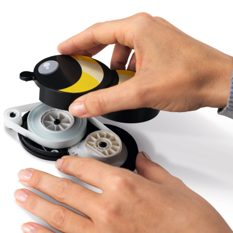 Una mano tiene un dispenser giallo e nero, mentre l'altra mano tira fuori il filo.