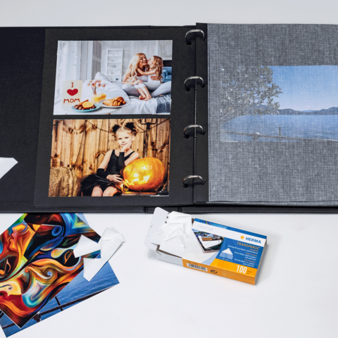 Un album fotografico con diverse immagini, tra cui ritratti e paesaggi, insieme a alcune cartoline fotografiche sfuse e un involucro di film.